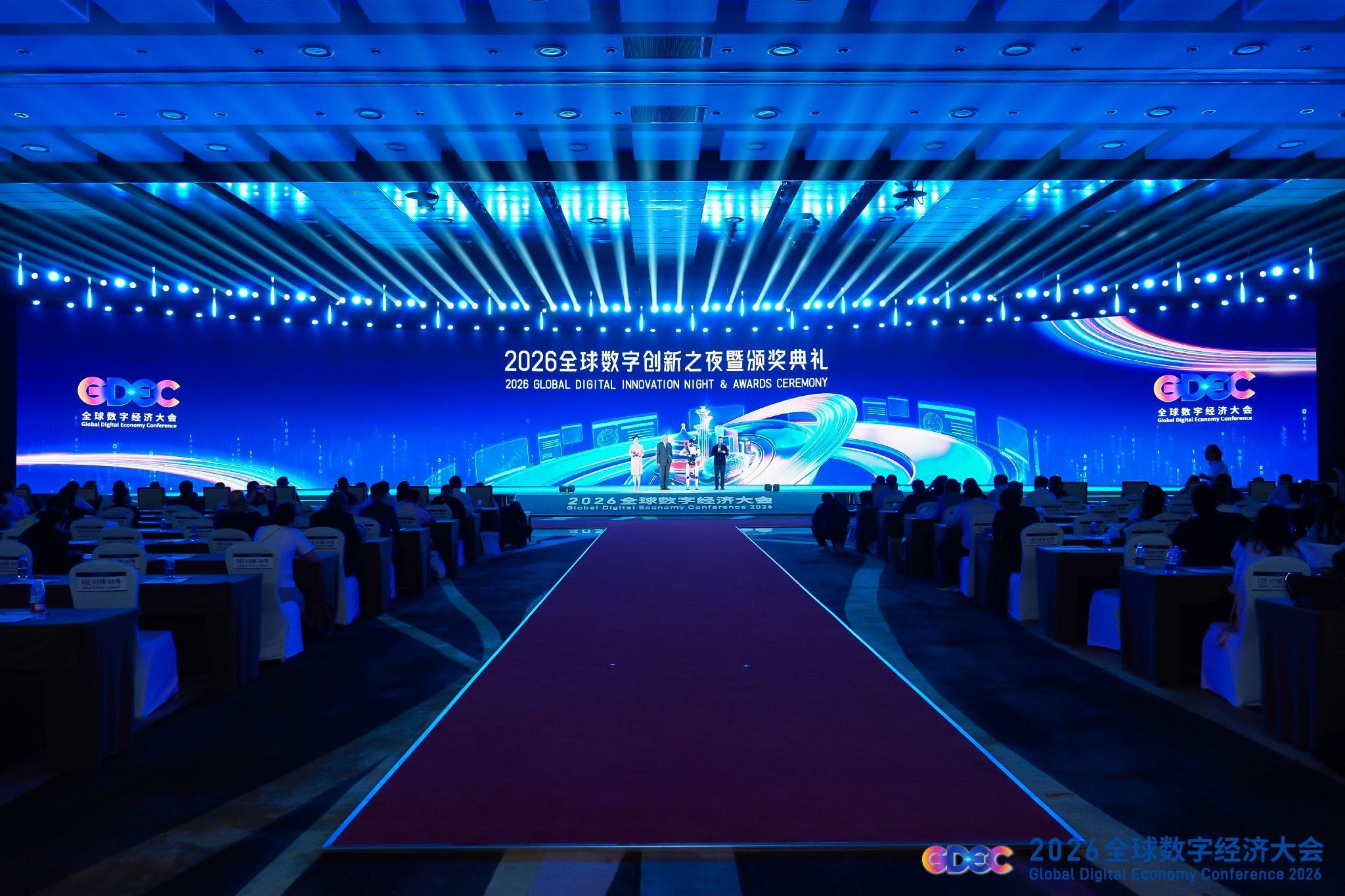 An audience sits in a conference hall facing the blue-lit 2026 Global Digital Innovation Night and Awards Ceremony stage.