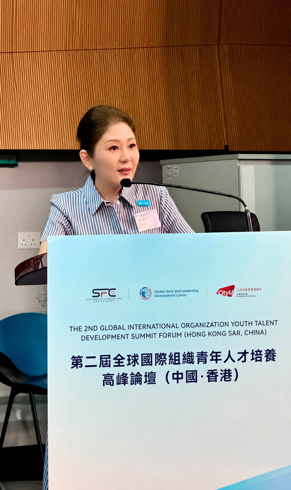 A Forum speaker stands at a podium with the event banner.