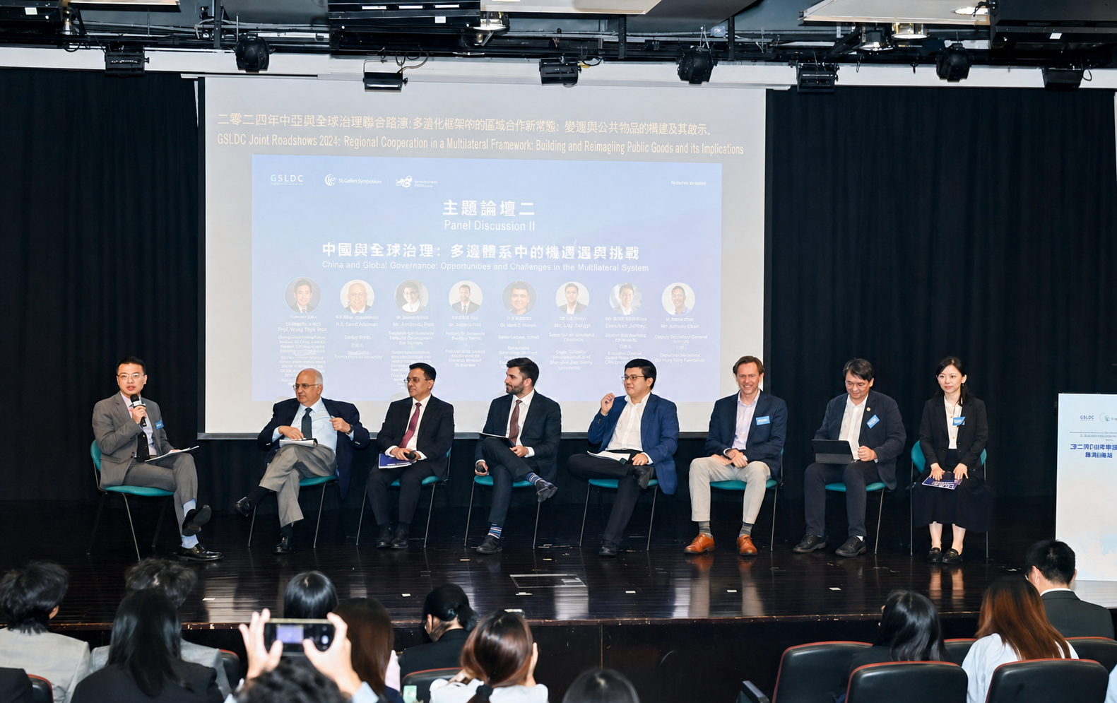 A multi-speaker panel takes place on stage before the Forum audience.