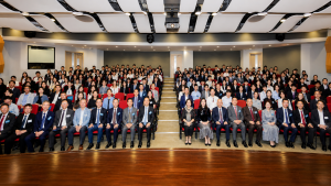 Enhanced editorial group photograph of delegates and speakers at the Global International Organization Youth Talent Development Summit Forum in a Hong Kong auditorium.